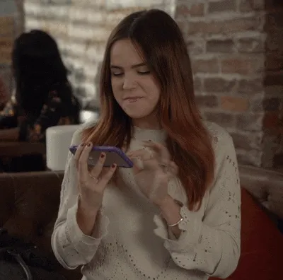 A woman smiling as she taps on her smartphone